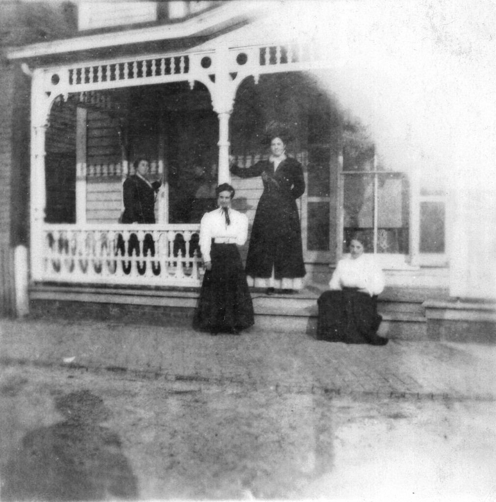 Photo of Lydia Ann Black in front of family home, seated at right.