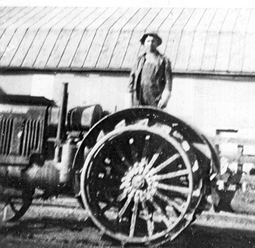 John S. Isaacs on early model gasoline-powered tractor, ca. 1930